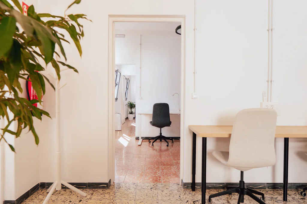 Puesto con silla tapizada junto a la puerta de otra sala de trabajo.
