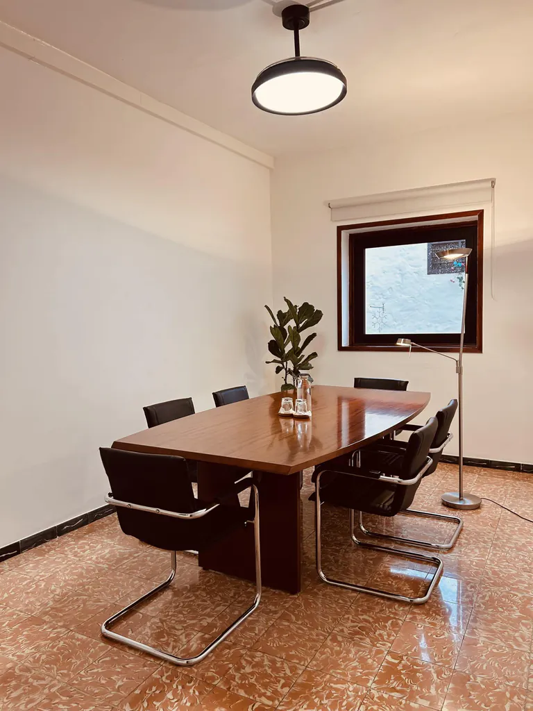 Sala de reuniones con mesa para seis personas y ventana.