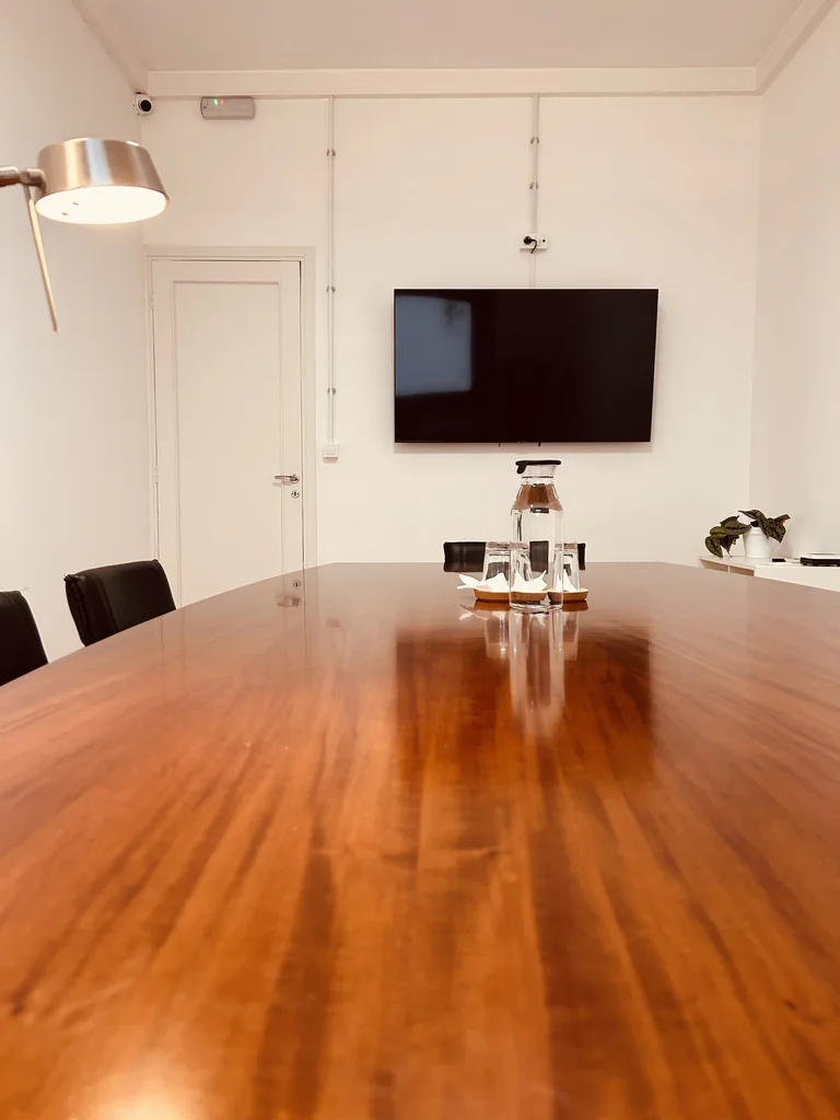 Sala de reuniones con pantalla en la pared, vista desde la mesa.